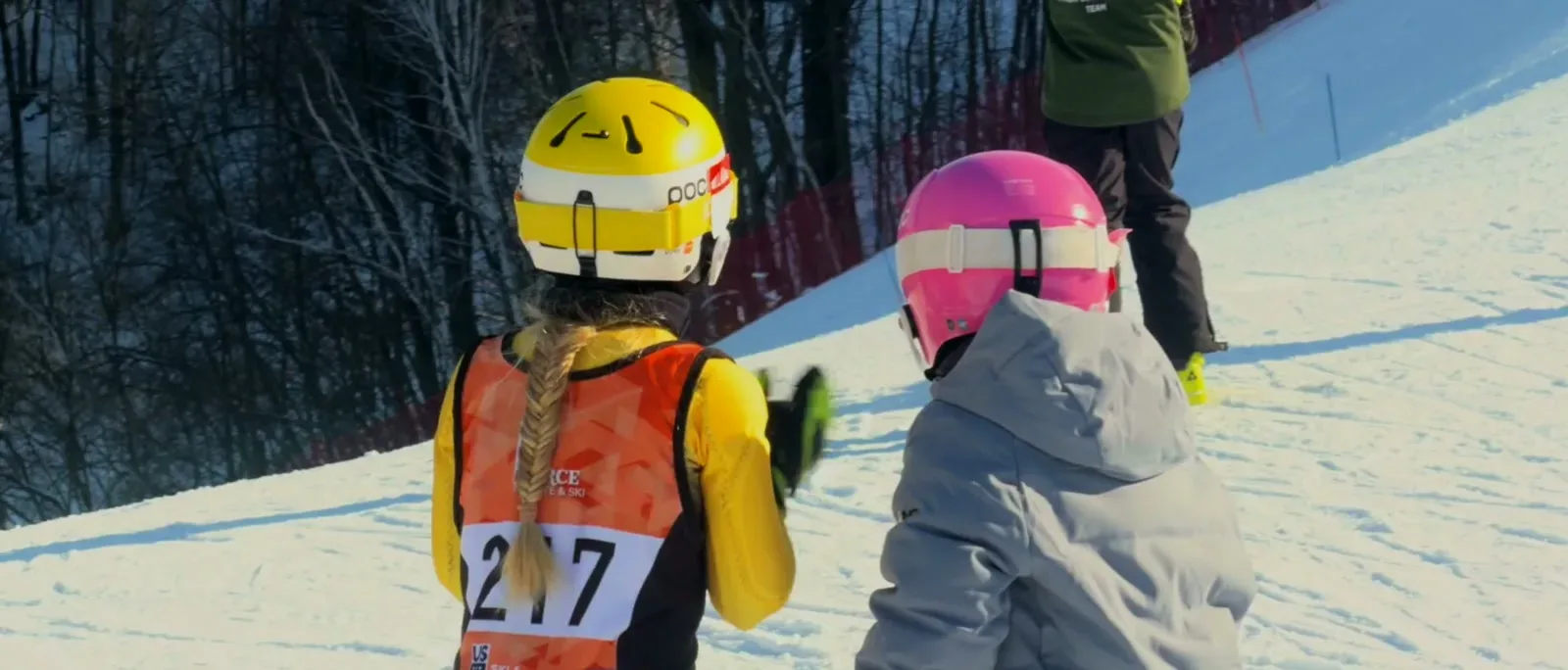 Young racers in helmets lying in the snow between runs
