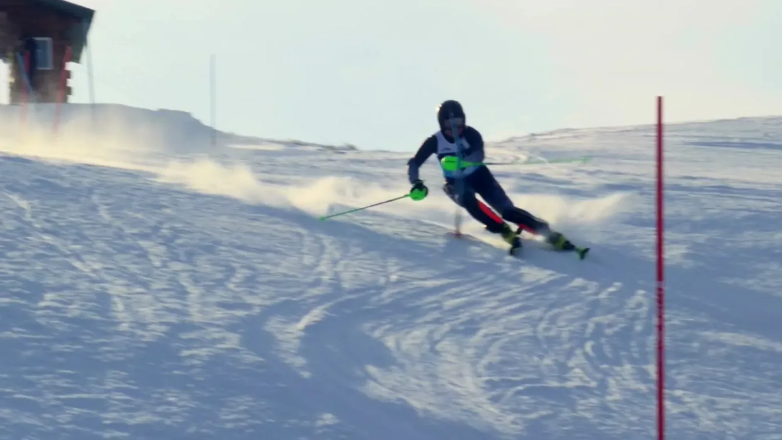 A racer drives through a giant slalom gate at sunrise