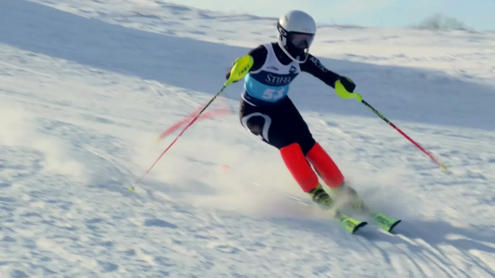 A racer in a white helmet drives through a slalom gate