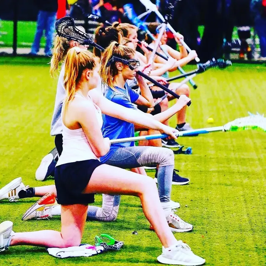 KC Elevate girls kneeling in a line with their sticks raised during training