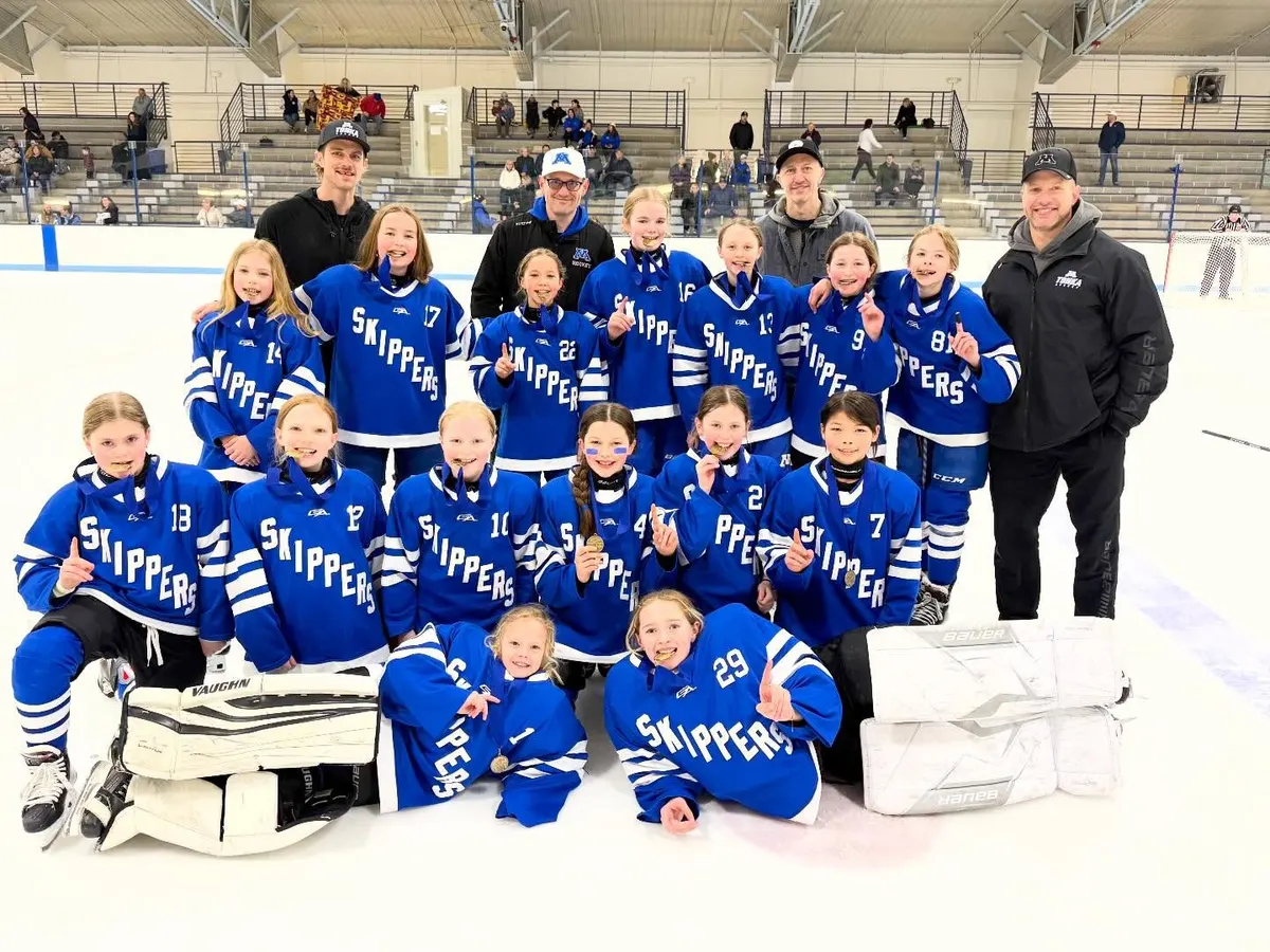 A Minnetonka 10U girls team in blue Skippers jerseys with its coaches