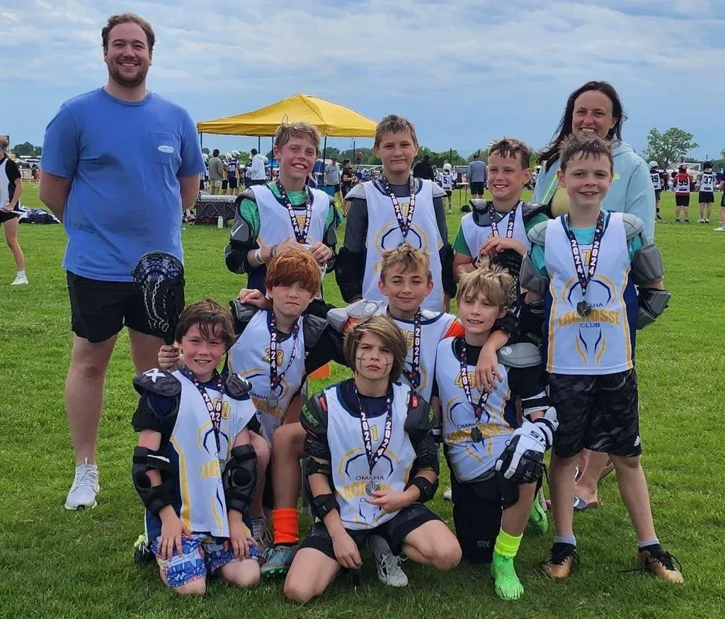 An Omaha Lacrosse Club youth team with their coaches after a spring game