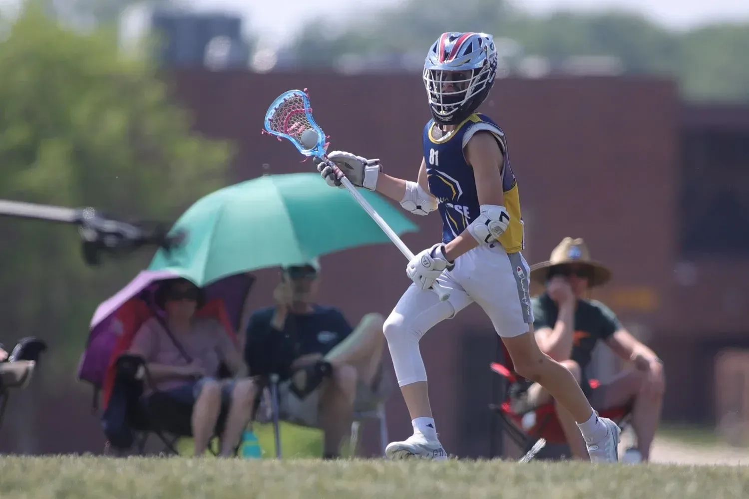 An Omaha Lacrosse Club player carrying the ball upfield in a spring game