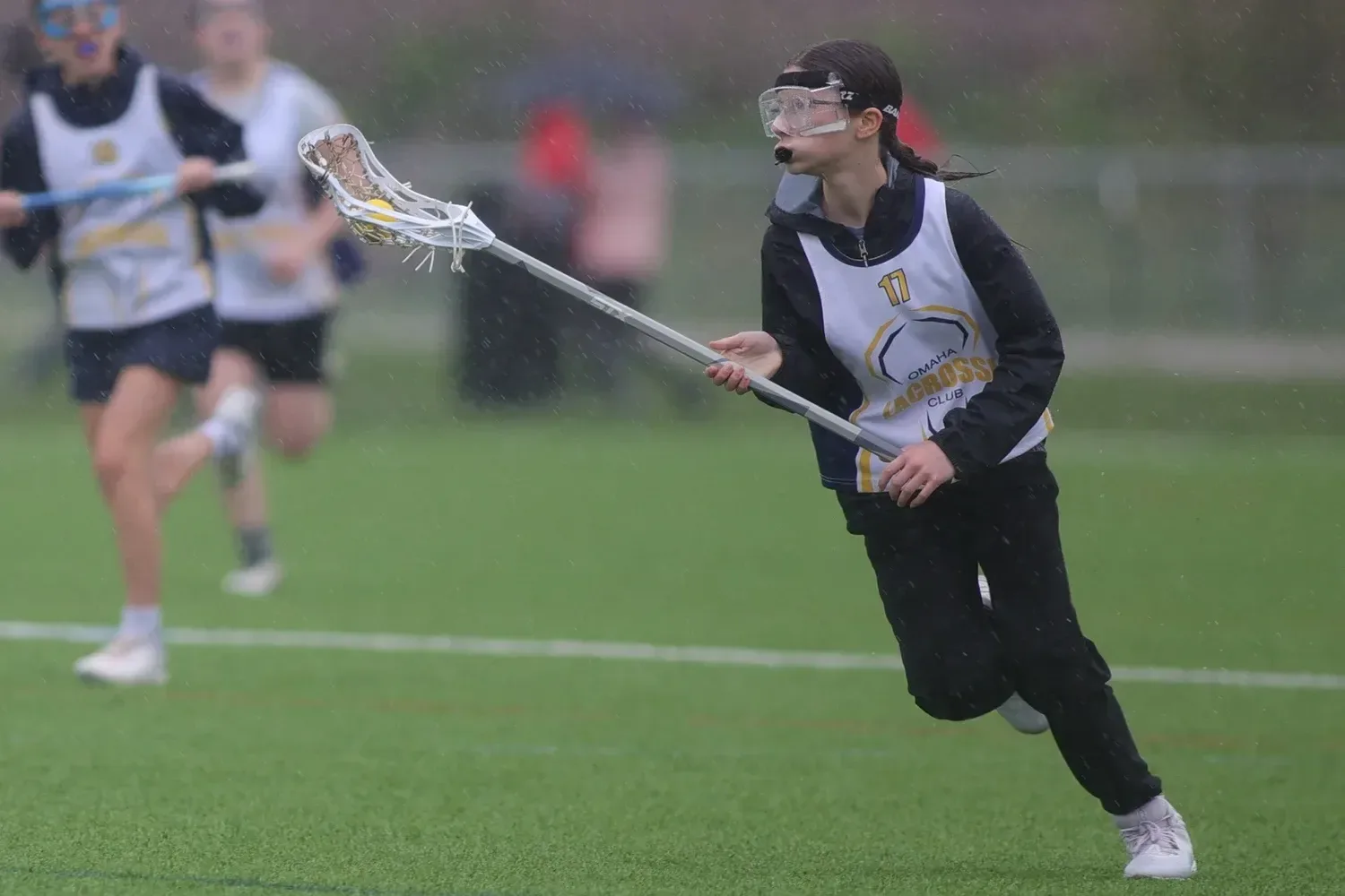 A young Omaha Lacrosse Club player running with her stick