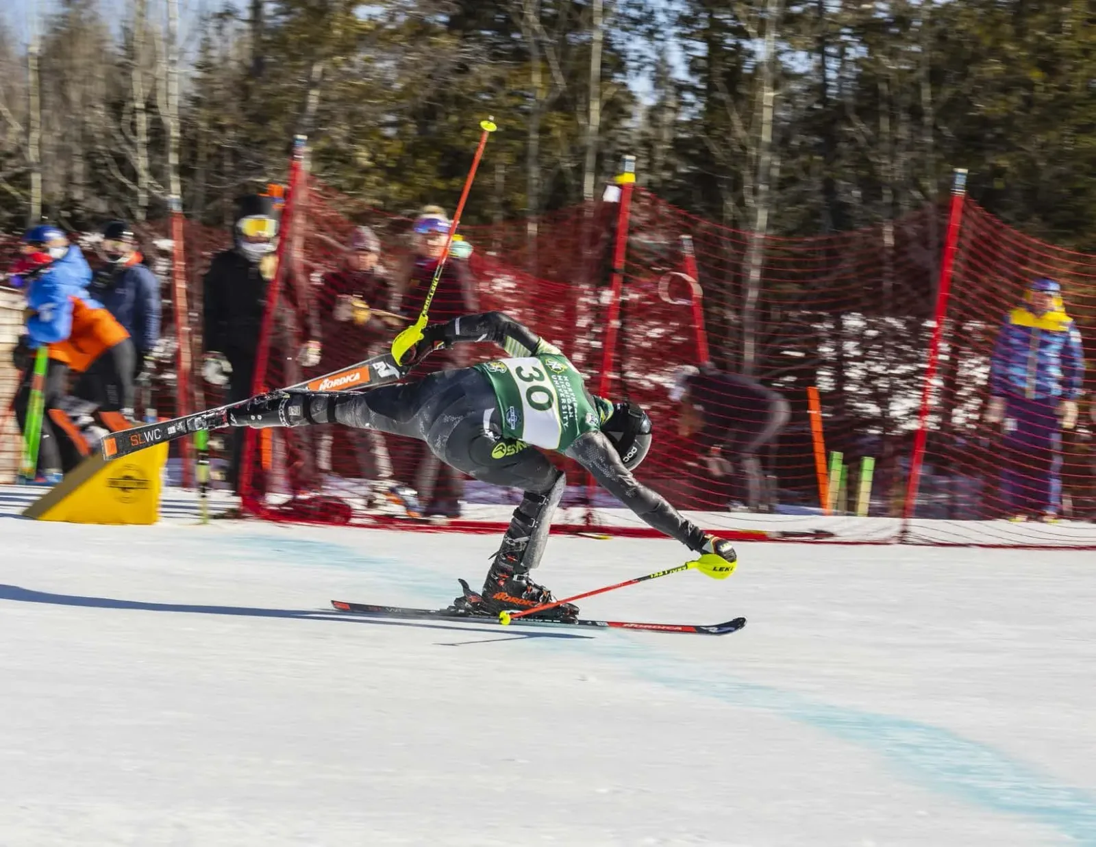 A racer clearing a slalom gate in front of the race fencing