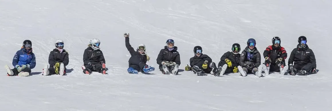 Team Gilboa racers sitting together on the snow in team jackets